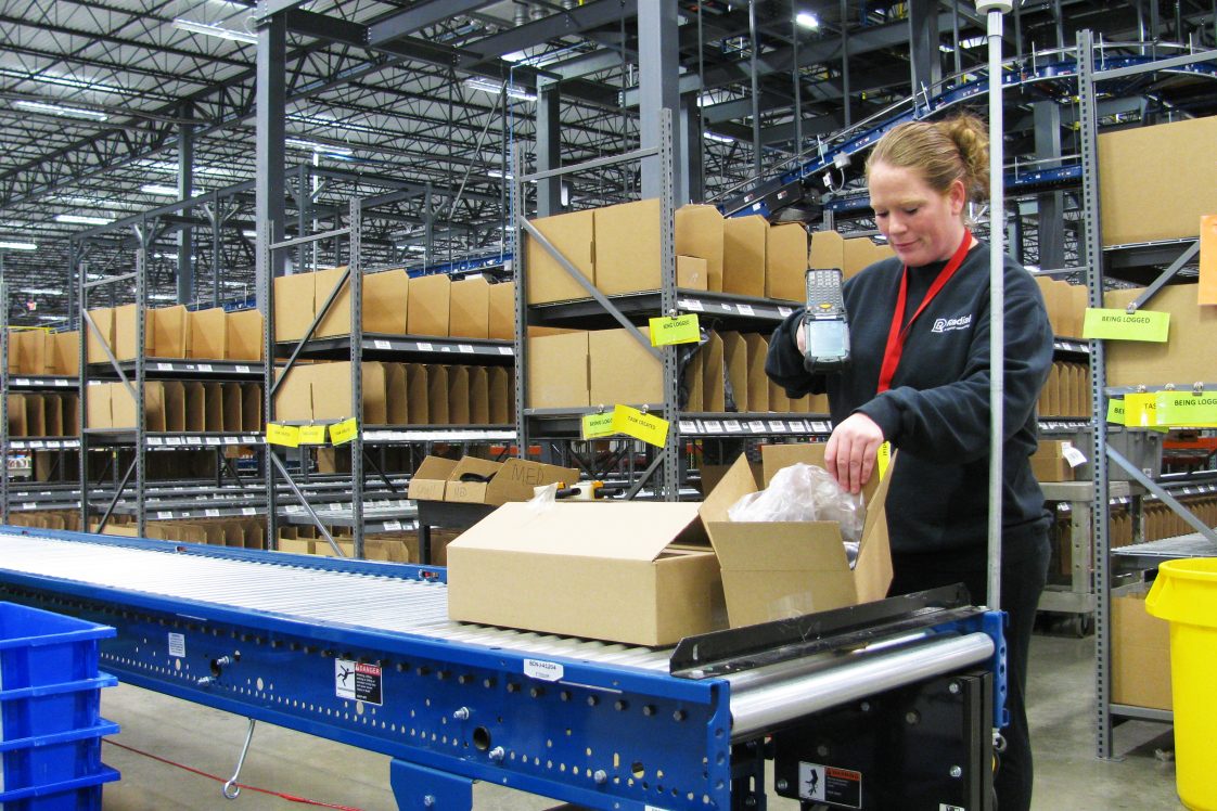 radial warehouse employee working on returns by scanning packages