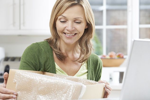 woman opening package in front of laptop