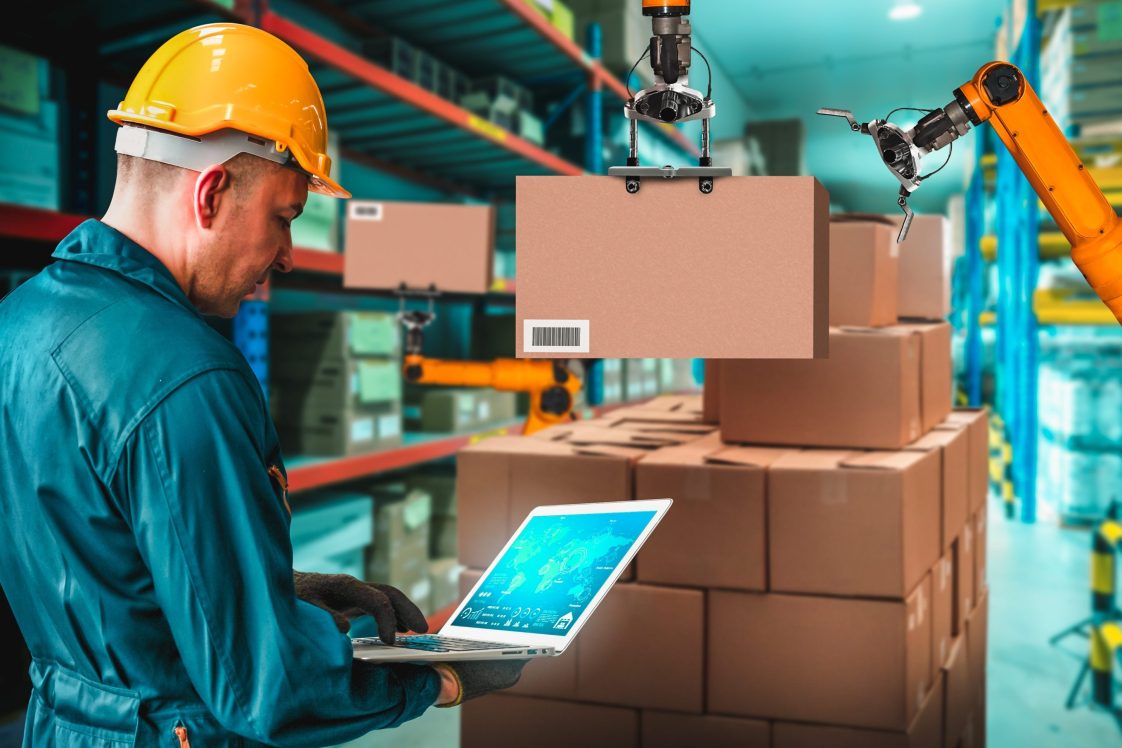 robot arm picking package while warehouse worker looks on