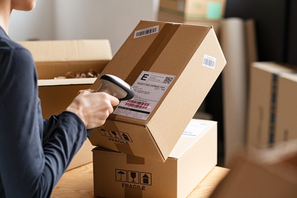 delivery worker scanning a package barcode with a scanner gun