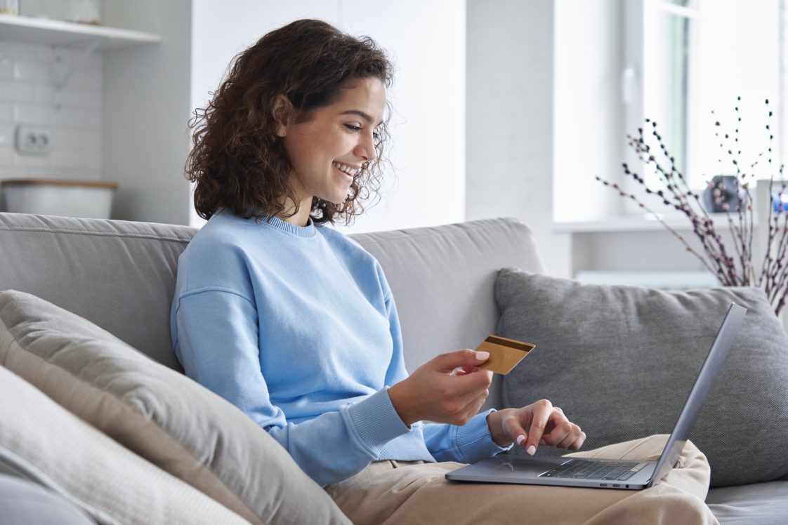 smiling woman holding a credit card and shopping on her laptop