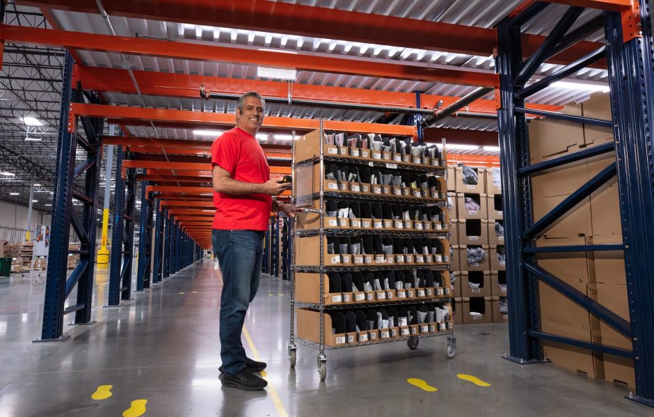 male radial worker in fulfillment warehouse sorting packages on a rack
