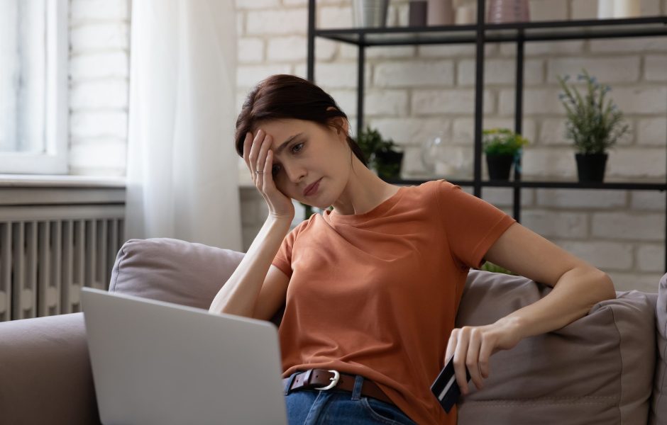 frustrated woman holding credit card and looking at laptop