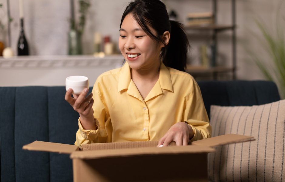 happy woman opening a box and holding cosmetic cream