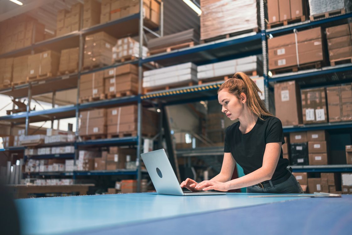 woman on computer doing inventory management in warehouse