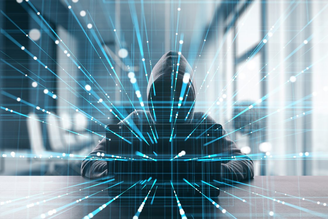 hacker in dark clothing working on computer