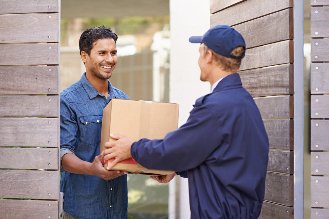happy man receiving a package at the door from last mile delivery driver