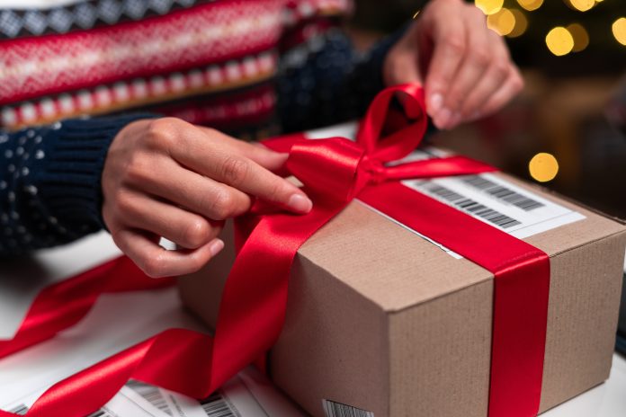 person opening a package with bright red bow