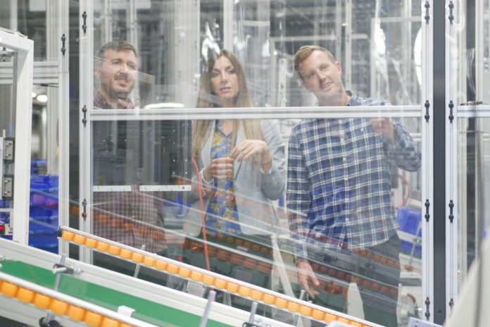 three people in fulfillment center looking at robotic automation
