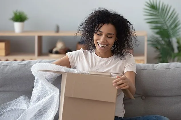 happy woman opening box she received from carrier