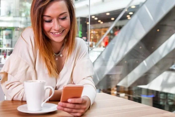 woman drinking coffee and reading phone