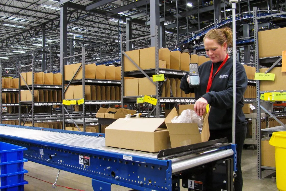 fulfillment center worker scanning a package on a moving line
