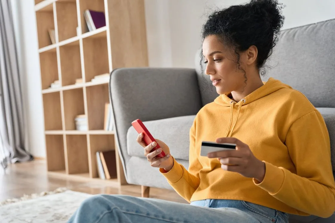 woman shopping on her phone holding a credit card