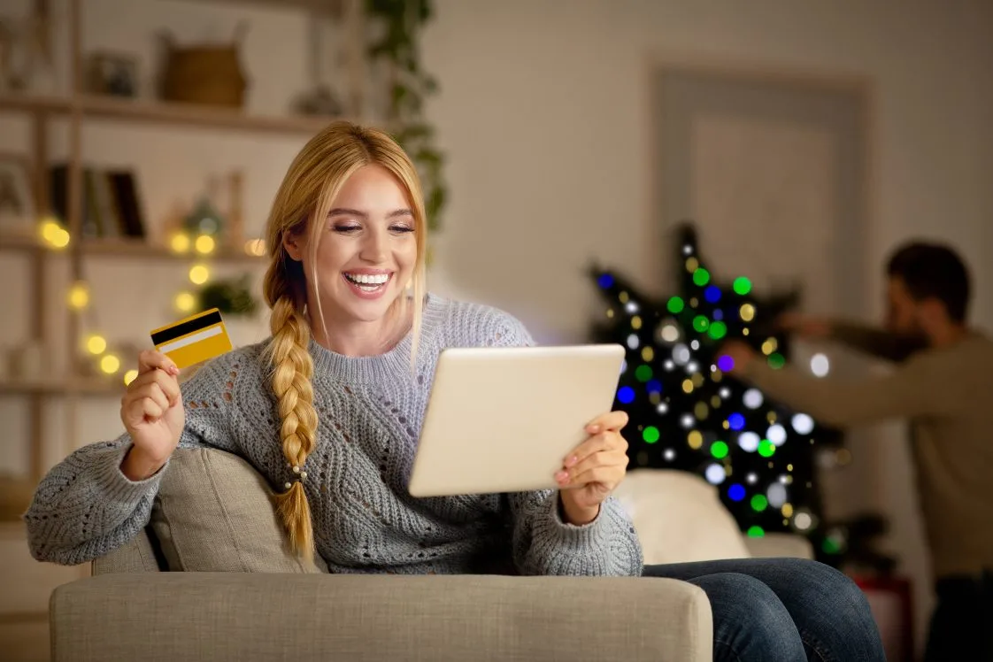 happy woman shopping on tablet holding credit card