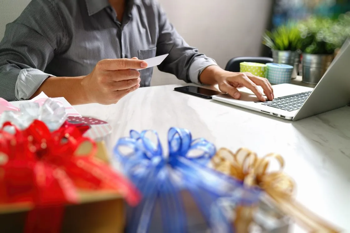 person holding credit card holiday shopping on laptop