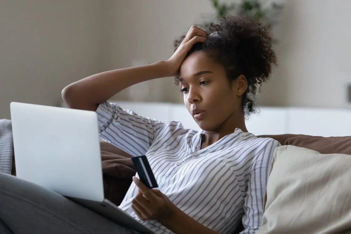 frustrated woman on laptop holding a credit card