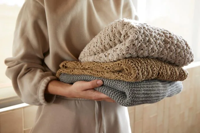 Hand holding a stack of sustainable cloths in tracksuit, homemade and Eco friendly fabric