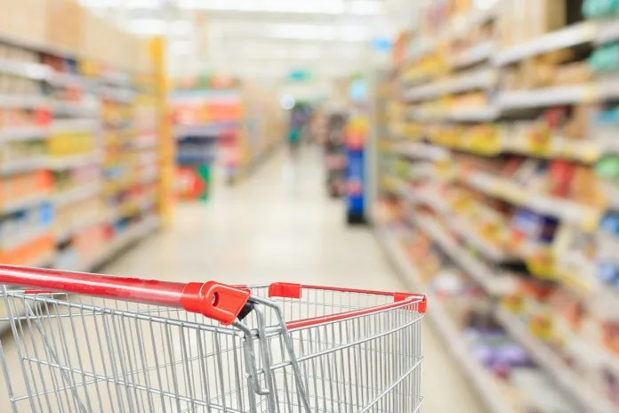 Shopping cart in an aisle full of consumer packaged goods.